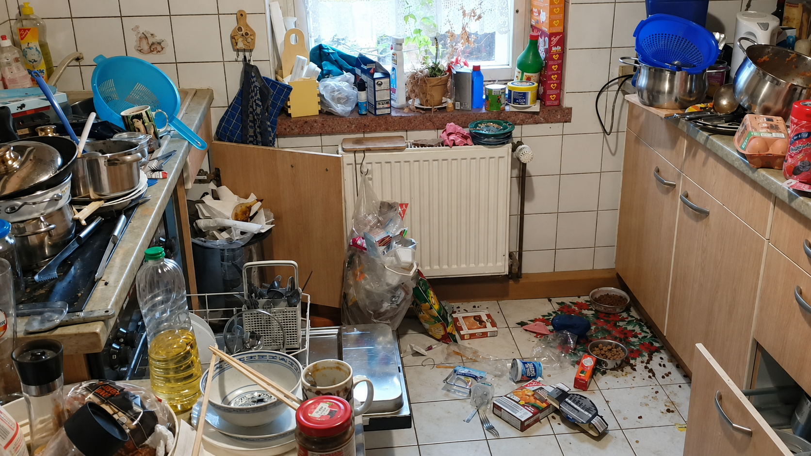 Küche vor der Grundreinigung mit stark belegten Arbeitsflächen und verschmutztem Boden